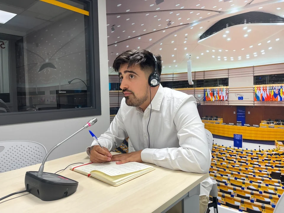 Lincoyan Parada at an interpreting booth with a microphone and notebook