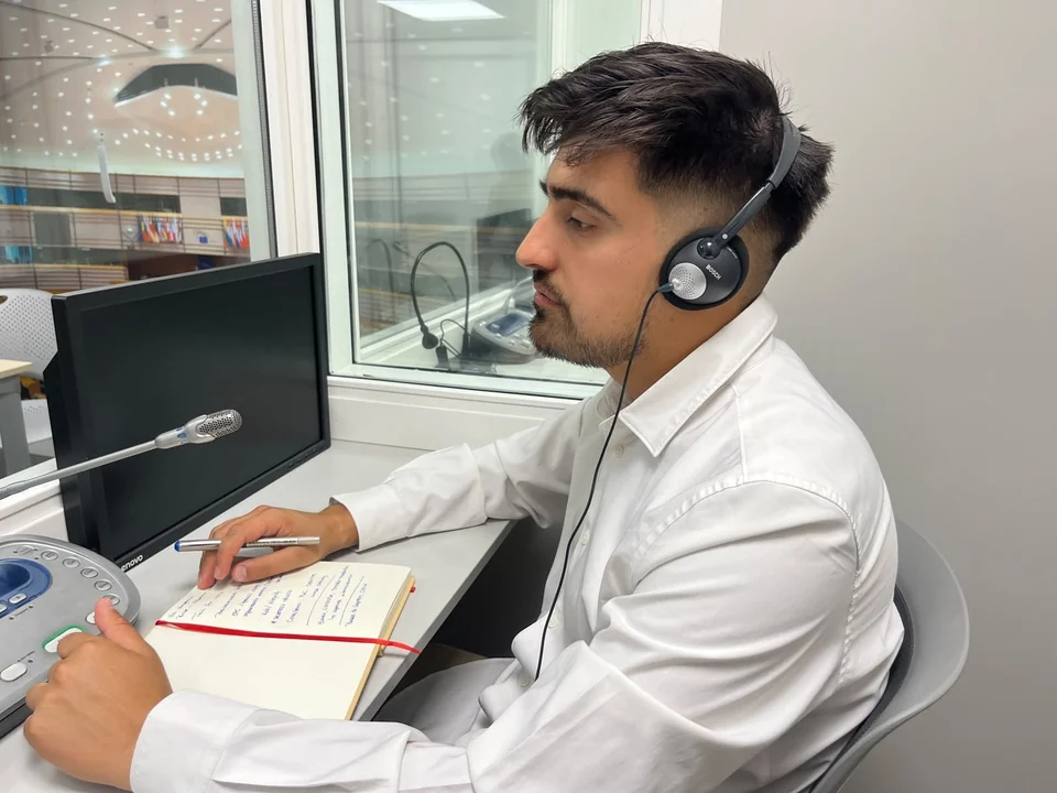 Lincoyan Parada listening through headphones with a microphone and notes at hand